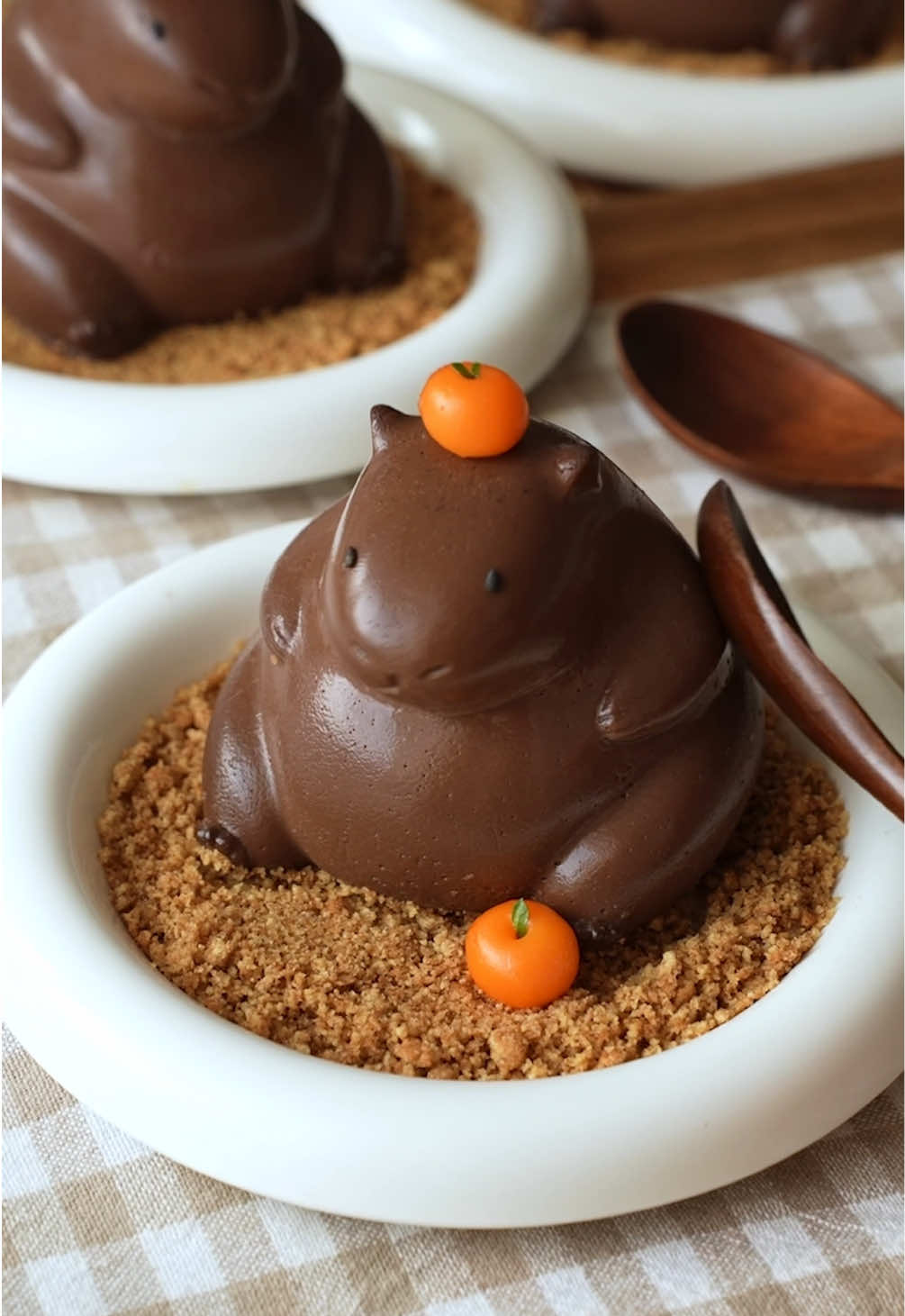 Capybara Chocolate Pudding 🐾🍊🍫 You’ve probably have already seen these adorable jiggly capybara chocolate puddings, but have you seen them with an Orange dango on its head and hojicha sauce?? I don’t think so 🤚🏻 Me neither, that’s why I made it hehehe Ingredients: Capybara Pudding - 20 g unsweetened cocoa powder - 50 g sugar  - 2 tsp agar agar powder  - 540ml milk - 80g dark chocolate - Black sesame seeds for the eyes - biscoff cookies Optional:  Orange Dango - 10 g shiratamako  - 8 ml water - Yellow or orange food coloring  - Mint leaves  Hojicha Sauce: - 5 g hojicha powder - 30 ml water  - 30 g sugar - 70 ml heavy cream 1. In a saucepan, combine cocoa powder, sugar and agar agar powder. This helps prevent clumping later. 2. Add milk and mix until smooth. 3. Place over medium heat, bring to a gentle boil and let it simmer for 2 minutes, whisking constantly. 4. Reduce the heat to low and stir in the dark chocolate until completely melted and smooth. 5. Pour the mixture into 3 capybara molds. Tap lightly to remove air bubbles. 6. Let the puddings cool at room temperature for 15 minutes, then transfer to the refrigerator overnight.  7. When the pudding has set completely, gently peel off the mold. 8. Decorate with black sesame for the eyes and serve with crushed biscoff cookies. 9. Optional:  - Orange dango: make onrage dango by combining glutinous rice flour, water and food coloring. Roll them into small balls. Add to boiling water and wait until they float to the surface. Transfer to ice cold water and add a mint leaf. There you have your orange dango!  - Hojicha sauce: whisk together hojicha powder and water (like you would prepare a matcha) and add to a saucepan with heavy cream and sugar. Mix until thickened.  #capybara #chocolatepudding #capybarapudding #hojicha  