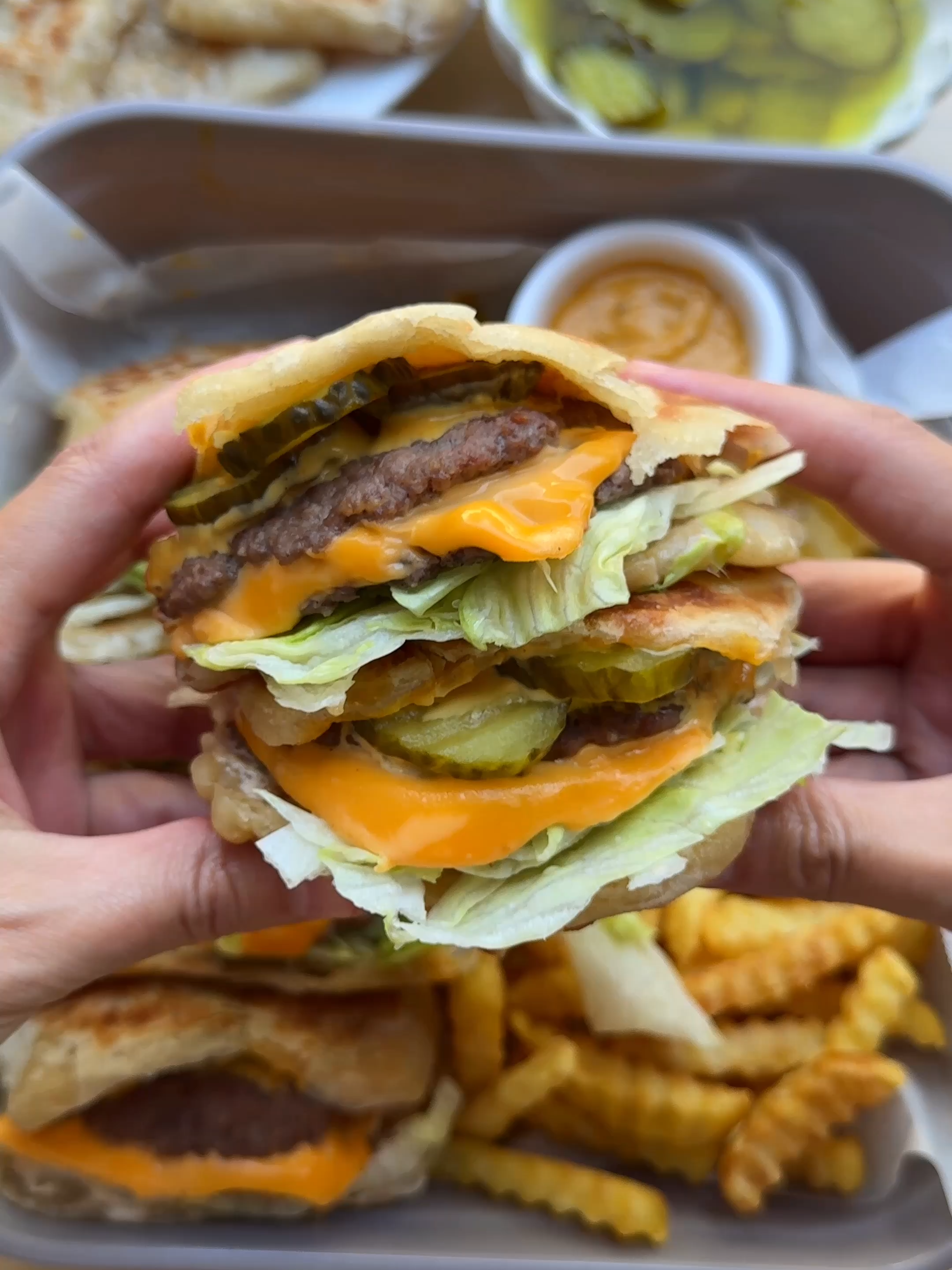 MSMEN BURGERS #food #recipe #burger #msmen #moroccan #beef #foryou #foryoupage Paratha burgers are having their moment, but msmen is the Moroccan alternative you need to try. Flaky, buttery layers of msmen loaded with juicy burgers, melty cheese, and a punchy sauce; it’s crispy, soft, and totally addictive. A bold twist that takes the burger game to the next level! DOUGH 400 g flour (all-purpose flour) 6 g salt (1 teaspoon) 25 g unsalted butter 12 g honey 215 ml lukewarm water GROUND BEEF 400 g ground beef 3 g salt (½ teaspoon) 1 g black pepper (⅓ teaspoon) cheddar cheese SAUCE 125 g mayonnaise 25 g mustard 30 g ketchup 25 g pickles 10 ml pickle juice SERVE WITH lettuce sauce pickles   EXTRA  sunflower oil (for greasing) Put the flour and salt in a bowl. Add the butter, honey, and water. Knead for 10–12 minutes until smooth.  Cover and let it rest for 30 minutes. Divide the dough into 10 equal pieces of about 65 g each and shape them into balls. Grease your hands with oil and take one ball of dough. Press it flat on a greased surface (about 30 ml oil). Cover and let it rest for another 30 minutes. Grease your work surface again with oil (about 15 ml per msmen). Spread the dough out with your fingertips into a very thin sheet, about 38 × 33 cm. Keep your hands oiled to prevent tearing. Use a pizza cutter to make 6 small cuts along the edges to make folding easier. Fold each sheet of dough. Place the msmen on a greased baking sheet. Cook the msmen in a skillet over medium heat until golden brown and cooked through on both sides. Put the ground beef in a bowl. Add the salt and black pepper. Mix well. Take a portion of the beef and flatten it with your hands. Place the patties on a sheet of baking paper, cover with another sheet, and press flat. Repeat until all patties are shaped. Cook the patties in a skillet over medium heat for 1 minute on one side. Flip, place a slice of cheddar cheese on top, and cook for another minute. Mix the mayonnaise, mustard, ketchup, grated pickles, and pickle juice in a bowl until well combined. Open the msmen and fill with sauce, burgers, pickle slices, and lettuce. Bismillah, enjoy! Tips: Use lukewarm water, as it makes the dough more pliable and helps it rest faster. Knead the dough well. The longer you knead (10–12 minutes), the more elastic it becomes, making it much easier to roll out. Oil is your best friend when making msmen. Keep your hands and work surface well-greased to avoid tearing. Flatten the burgers using baking paper. Don’t cook the burgers too long. Since they are thin, 1 minute per side is enough. Otherwise, they will dry out. Add tomato slices, onion, or jalapeño for more variation. You can also make the msmen ahead of time and freeze them. Cook them briefly, let cool, and freeze.  Before using, reheat in a dry skillet. Super handy for a quick meal.