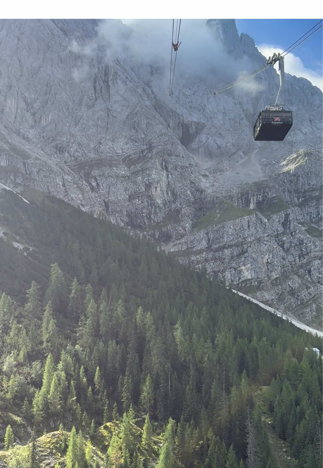 From the forest to the clouds – Zugspitze ascent 🌲☁️ Gliding above endless pine forests while climbing towards Germany’s highest peak, Zugspitze (2,962 m). The ride feels like stepping from nature into the sky itself. #Zugspitze #GermanyTravel #BavarianAlps #CableCarViews #IntoTheClouds   
