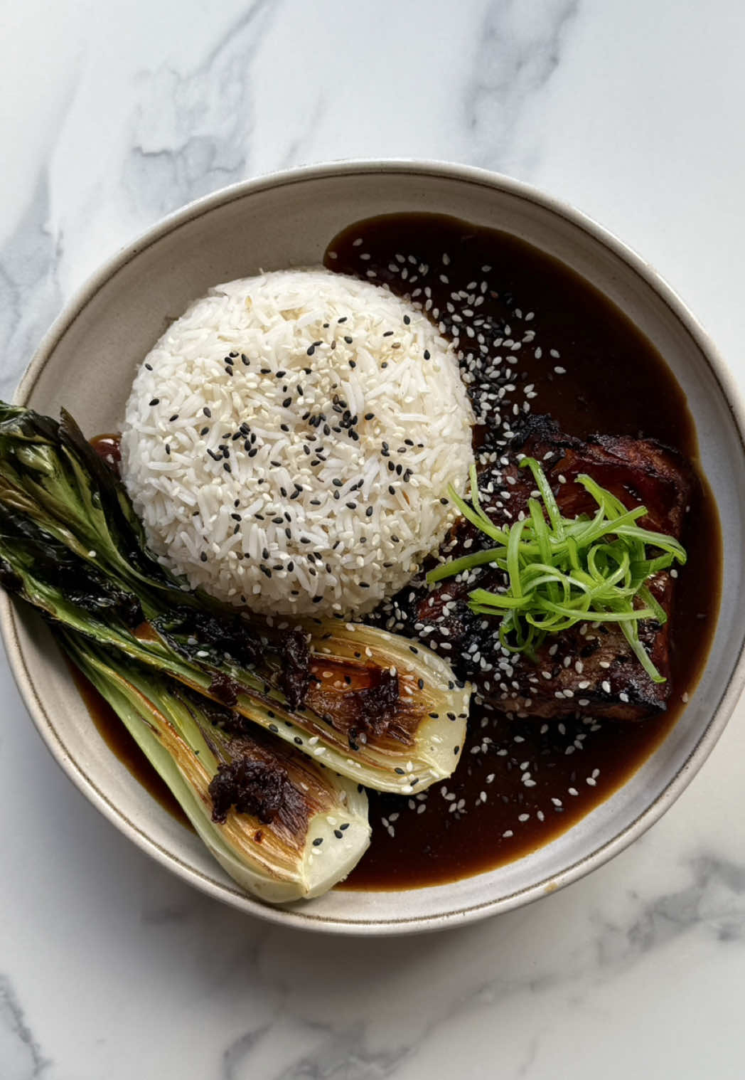 Miso glazed cod ft the viral brothy rice 🤌🏽🍚  Rich miso broth, charred pak choi, and a whole lot of nourishing comfort 🥰 (This would work really well with salmon, chicken or tofu too) Protein 46g / Calorie 579  Recipe:  -Mix 1 tbsp miso paste, 1 tsp dark soy, 1 tsp mirin or honey, and lil sesame oil, then coat the cod loin and leave to marinate for at least 20 mins.  -Cook the rice until fluffy and set aside.  -Heat a pan until hot, add a little oil, and sear the pak choi cut-side down for 3 minutes until lightly charred, then remove.  -Then sauté 1 minced garlic clove, 1 tsp ginger, and the white part of the spring onion for 1–2 minutes. -Pour in 250ml chicken stock, bring to a simmer, then whisk in 1 tbsp miso paste, 1 tbsp soy sauce, and chilli if using; taste and adjust. Add the pak choi to the broth to warm through.  -Preheat the grill to 220°C, line a tray with lightly oiled foil, wipe excess marinade from the cod, and grill in the top third of the oven for 6 minutes until golden, caramelised, and just cooked through. If you want, brush over some extra marinade in the last 2 mins for extra glaze. -To serve, place rice in a bowl, ladle over the miso broth, add pak choi, and the grilled cod. Garnish with spring onion greens, sesame seeds, a generous squeeze of lime + chilli oil 😋 #EasyRecipe #brothyrice #misocod #healthyrecipe #highprotein  