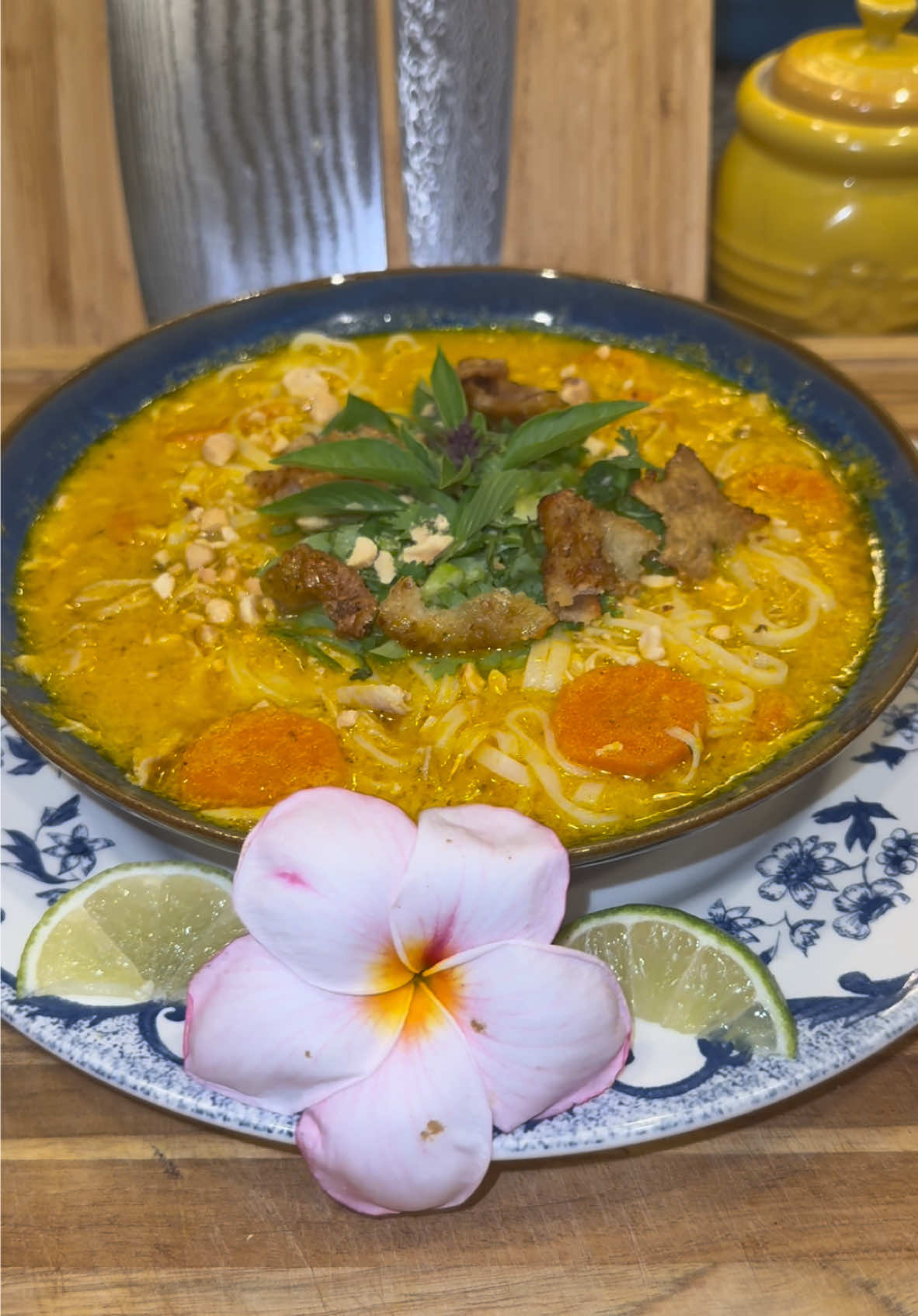 Thai inspired Chicken Noodle Soup🍲   #Recipe #soup #chickennoodlesoup #comfortfood #thaifood  In a large pot on medium heat with oil add: -1 large onion (roughly chopped) -3 large carrots (peeled and roughly chopped) -1/4 cup worth of peeled and cubed ginger  -14 cloves of garlic  Cook until the onions are soft then add it all to a blender with: -One 13.5 ounce can of coconut milk  -1/2 cup of Mirin  Blend until smooth.  Then in the same pot, brown up 2.5 pounds of bone-in skin on chicken. (I always use thighs, and I like to separate the skins and fry them up until they’re crispy to use as a topping for the soup) Then add in everything from your blender into the pot, along with 4 cups of chicken bone broth or chicken stock.  Then season with: -pepper -chicken bouillon  -some chili powder (if you want it to have a kick.) Bring it to a boil, turn the heat down to low, and cook covered for 45 minutes.  At the 20 minute mark, I like to also add in about 3 carrots peeled and sliced into rounds.  When it’s done, remove your chicken and shred it up into the soup (once it’s cooled down enough.) You can also add more broth or water to the soup if it needs to be thinned out.  Then add cooked rice noodles to a bowl, top it with your hot soup, and then add in the aromatics.  I like to use: -Thai Basil  -green onion -cilantro  Then finish it off with: -crushed peanuts -your crispy chicken skins -a squeeze of fresh lime juice  Enjoy💜
