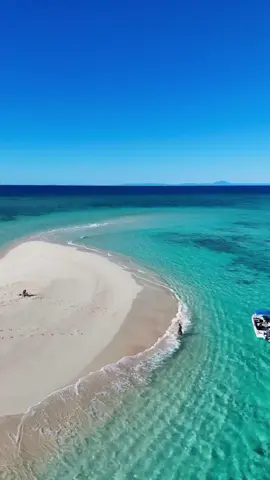 The Great Barrier Reef is home to around 300 sand and coral cays, and they make for quite the unique beach day destination 🏖️  🎥: @LISA KELLER 🌺 TRAVEL + UGC  📍: Mackay Coral Cay, @Tourism Port Douglas Daintree, @Queensland, Australia  #SeeAustralia #ComeAndSayGday #ThisIsQueensland #PortDouglas ID: An aerial of two people on a large white sand cay surrounded by clear turquoise water with a small boat parked in the shallows.