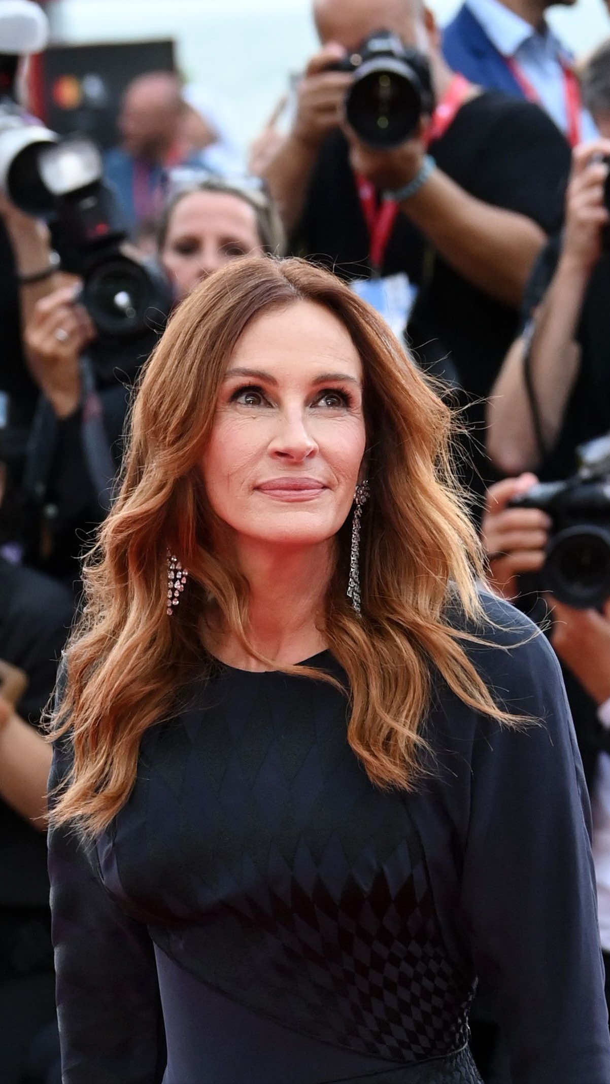 Il primo red carpet veneziano di Julia Roberts era tra i più attesi di questa 82ª edizione della Mostra Internazionale d'Arte Cinematografica organizzata dalla Biennale. In Laguna per presentare il nuovo film di Luca Guadagnino, After the Hunt, la diva hollywoodiana ha però scelto di sfoggiare un look sobrio, forse fin troppo. Per il tappeto rosso che ha preceduto la proiezione della pellicola, Julia ha infatti optato per un long dress blu navy di Versace by Dario Vitale, rappresentando di fatto non solo il suo debutto al Festival di Venezia ma anche quello della nuova direzione creativa della maison della medusa. Trattasi di un custom atelier Versace in crepe de chine, caratterizzato da un ricamo con motivo damier in seta nera, che contribuisce a conferire un senso di dinamismo tridimensionale all’abito. Un ricamo che ha visto l’impegno di ben 300 ore di lavoro. Un lavoro sartoriale sicuramente certosino per un abito ben fatto ma che purtroppo non ci convince. Forse per l'attrice dal sorriso più radioso del cinema ci saremmo aspettati qualcosa in più, soprattutto con indosso un abito del marchio simbolo del glamour e della seduzione nel mondo. E invece possiamo tranquillamente ammettere che siamo rimasti un po' delusi. Del resto, capita anche ai migliori. ————————— Julia Roberts' first Venetian red carpet was among the most anticipated of this 82nd edition of the Festival. In Laguna to present Luca Guadagnino's new film, After the Hunt, the Hollywood star has chosen to show off a sober look, perhaps too much so. For the red carpet that preceded the screening, @juliaroberts opted for a navy blue long dress by Versace by Dario Vitale, representing not only her debut at the Venice Film Festival but also that of the new creative direction of the maison. This represent huge a sartorial work that is certainly a well-made dress but which unfortunately does not convince us. Perhaps, for the actress, we would have expected something more, especially by a brand that symbolizes glamor and seduction. And instead we can safely admit that we were a little disappointed. After all, it happens even to the best. [📷 IPA] #whoopsee #juliaroberts #venezia82 