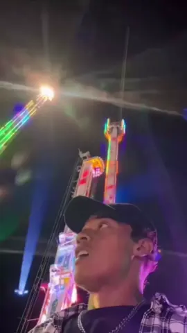 En plena feria nocturna, un chico se graba modo selfie cuando la atracción justo detrás le pasa muy cerca, muy rápido. Sólo perdió la gorra, por suerte