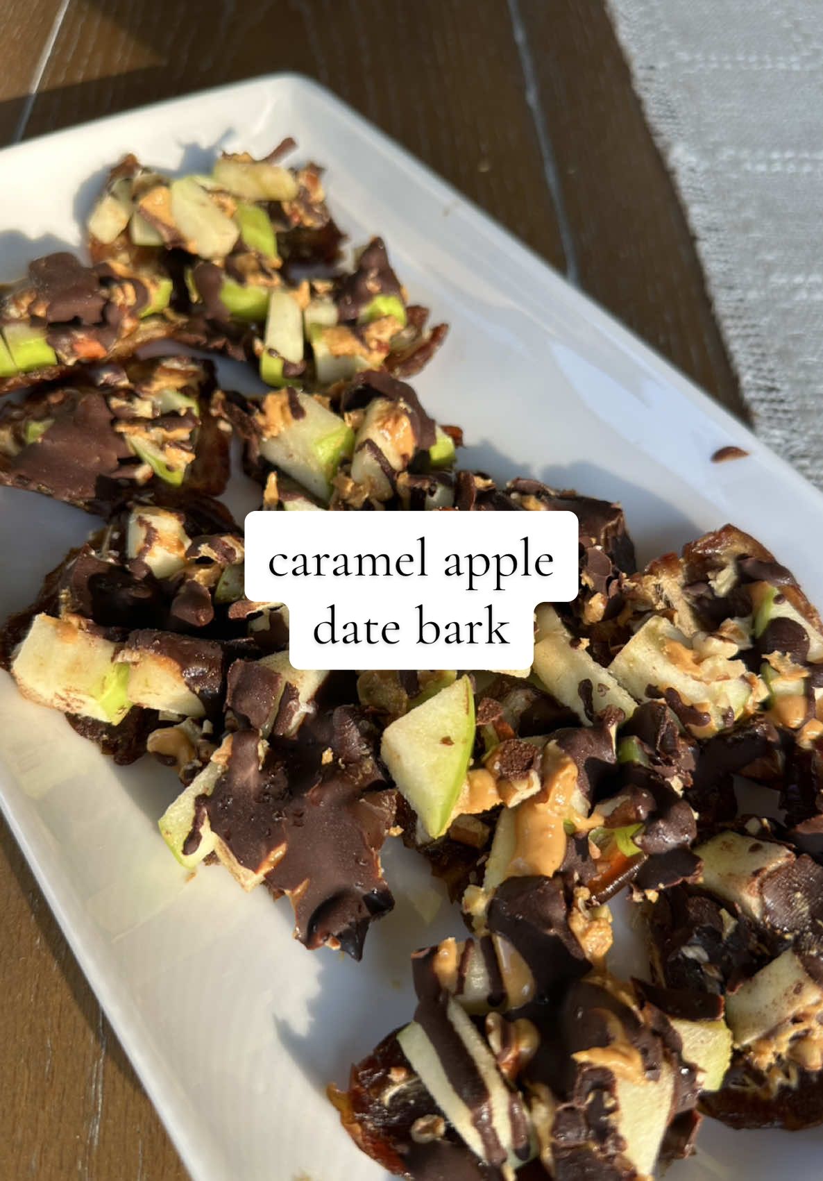 Meet your new favorite fall dessert! This Caramel Apple Date Bark has all the cozy flavors of caramel apples 🍏 made healthier with dates, crisp Granny Smith apples, pecans, and a drizzle of peanut butter & dark chocolate. The perfect easy sweet treat to make this season! ✨🍫 Ingredients: -12 pitted dates -1/2 of a Granny Smith apple diced -1/3 c dark chocolate chips (I like Lily's) -1 tsp coconut oil -2-3 tbsp of natural* peanut butter -1/4 c chopped pecans -flaky sea salt   Steps: 1. On a parchment lined flat tray or plate, layout 12 dates in a 3x4 sequence so that they are touching. 2. Lay a second piece of parchment paper on top of the dates and roll out the dates so they are completely flat. 3. Lift the top parchment carefully and reposition any dates if needed, then lay the parchment paper over the dates again and roll out again.  4. Once dates are joined in a flat sheet, top with diced apples & chopped pecans. 5. Heat chocolate & coconut oil in microwave for 30 seconds, mix, then heat for 15 seconds and mix again. Continue to heat in 15 second increments mixing in between until chocolate is completely melted. 6. *If you are not using natural peanut butter, heat peanut butter in the microwave in 10 second increments mixing in between until peanut butter is a similar consistency to the melted chocolate. 7. Drizzle peanut butter, then chocolate over apples and pecans. 8. Top with flaky sea salt. 9. Freeze for 1-2 hours or until chocolate and peanut butter have hardened. 10. Once frozen, break or cut into 12 pieces. 11. Store in airtight container in freezer.  12. Eat right out of the freezer or remove for ~15 minutes before eating for a softer consistency.  #caramelappledatebark #datebark #healthydesserts #healthysweettreat #falldesserts       