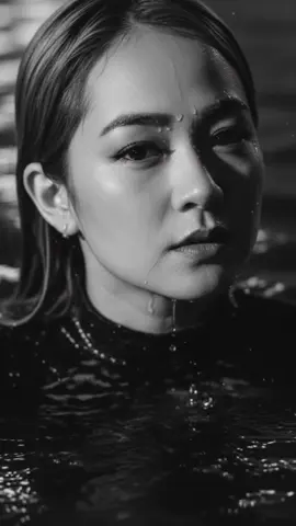 #geminiai #ai Generate a black and white close up portrait showing emerging from water. without changing my face. Her skin and hair should be wet, with visible water droplets and small bubbles. Use dramatic lighting to highlight the illuminated side while leaving the other side in deep shadow. Emphasise the texture of her skin and sharp eye detail. The mood should feel intense and cinematic, with a dark, minimal background.