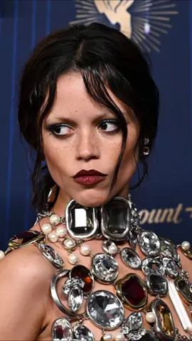 Jenna Ortega setzte bei den Emmys 2025 ein modisches Statement – ein zart schimmerndes Ensemble, das in seiner Kühnheit zwischen Glamour und Gothic changierte. Ortega erschien in einem Givenchy Outfit von Sarah Burton: Ein Top vollständig bedeckt mit Kristallen, Perlen und Juwelen, kombiniert mit einem schwarzen Rock mit hohem Schlitz. Ihr Styling betonte den Look mit dunklem Lippenstift, rauchigen Augen und einem zurückgebundenen Pferdeschwanz. 🖤 #JennaOrtega #Emmys2025 #Givenchy #RedCarpet #GlamGoth 