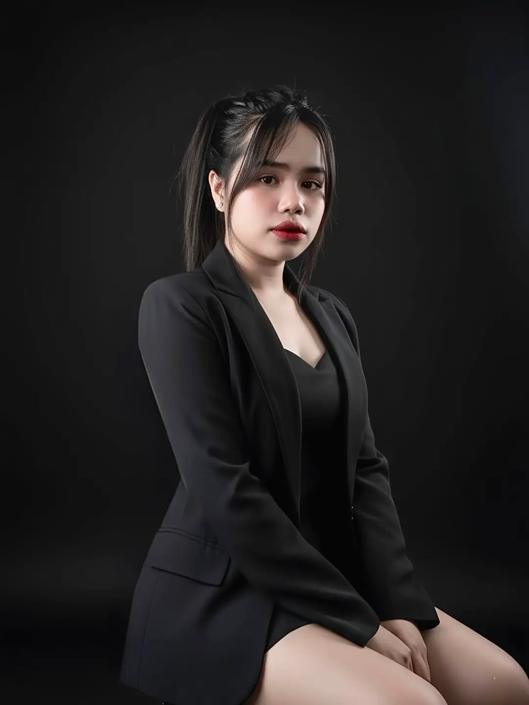 Edit foto ini menjadi duduk sampai di studio foto iya mengenakan orang outfit serba hitam Blazer oversize dan rok pendek Anggle dari depan Gaya elegan dan Edgy bernuansa misterius #Gemini #foryou #fyp @Aquarius 27 