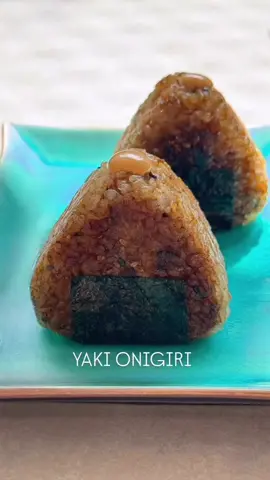 Yaki Onigiri 🍙  Não tem como resistir ao charme desse bolinho japonês em formato triangular, né? ❤️ Yaki Onigiri (焼きおにぎり) é o onigiri grelhado. 🔥 Ou seja: é o bolinho de arroz japonês levado à frigideira ou à grelha até formar uma crosta dourada e crocante por fora, enquanto por dentro continua macio. Aqui eu fiz a versão simples, só com o arroz temperado e finalizada com shoyu, crocante e cheia de sabor. . . . Yaki Onigiri 🍙  🔸 INGREDIENTES 2 xícaras de arroz japonês (gohan) cozido Mix de tempero (a gosto): furikake de shiso, furikake de wasabi e gergelim torrado 1 pitadinha de sal Recheio 80 g de atum fresco picado na ponta da faca 1 col. sopa maionese Kewpie (ou caseira) Cebolinha a gosto ½ col. chá pimenta sriracha 1 fiozinho de mel Sal a gosto Para pincelar 2 col. sopa shoyu 1 col. sopa saquê mirin ½ col. chá açúcar Óleo neutro para grelhar 1 tira de nori para cada onigiri Rendimento: 4 onigiris 🔸 MODO DE PREPARO 	1.	Cozinhe o arroz conforme a embalagem. Misture o mix de tempero com uma pitadinha de sal e experimente. 	2.	Prepare o recheio: misture o atum fresco picado com a maionese, cebolinha, sriracha, mel e sal. 	3.	Modele os onigiris em formato triangular, colocando apenas uma colher de chá do recheio no centro antes de fechar bem. 	4.	Aqueça uma frigideira antiaderente com fio de óleo. Quando começarem a dourar, vá pincelando a mistura de shoyu, mirin e açúcar, virando até caramelizar e ficarem crocantes. 	5.	Finalize envolvendo cada onigiri com uma tira de nori e, se quiser, um pingo extra de maionese com sriracha no topo. 💡 DICA: pode rechear também com atum em lata (muito comum), salmão grelhado ou até cru, se preferir. Observação: para armazenar, embrulhe em plástico filme e mantenha na geladeira. #YakiOnigiri #Onigiri #comidajaponesa #receitafacil #receitas  