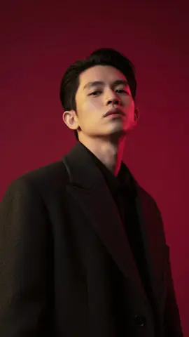 Prompt : Vertical portrait shot in 1080x1920 format, characterized by stark cinematic lighting and intense contrast. Captured with a slightly low, upward-facing angle that dramatizes the subject's jawline and neck, the composition evokes quiet dominance and sculptural elegance. The background is a deep, saturated crimson red, creating a bold visual clash with the model's luminous skin and dark wardrobe. Lighting is tightly directional, casting warm golden highlights on one side of the face while plunging the other into velvety shadow, emphasizing bone structure with almost architectural precision. The subject's expression is unreadable and cool-toned-eyes half-lidded, lips relaxed- suggesting detachment or quiet defiance. The model wears a heavy wool or felt overcoat, its texture richly defined against the skin's smooth, dewy glow. Minimal retouching preserves skin texture and slight imperfections, adding realism. Editorial tension is created through close cropping, tonal control, and the almost oppressive intimacy of the camera's proximity. There are no props or accessories; the visual impact is created purely through light, shadow, color saturation, and posture - evoking high fashion, contemporary isolation, and hyper-modern masculinity. #สร้างภาพด้วยai #ai #gemini #aigenerated #tiktok 