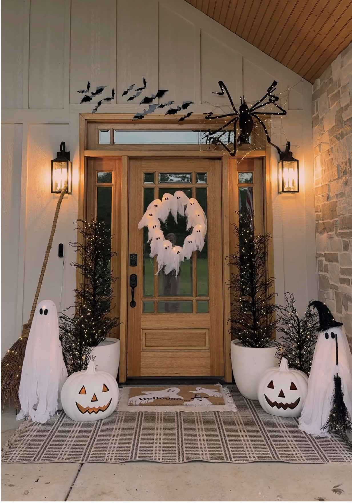 Halloween porch decor! 👻👻 I’ve already shared my Halloween porch from last year so I decided to do a new one this year!!🎃🎃 I figured I would  I did similar to last year’s porch with a few changes!! I decided to do a black and white theme! I started with a large rug, then layered a smaller white rug with a ghost coir mat! Then I added a large white planter with light up Halloween tree with a smaller Halloween tree beside it.  I also found these oversized jack o lanterns and thought they were sooo cute! I added some light up ghost on each side and a light up witches broom! On top of the door I added a light up spider web and a light up spider! I thought it was so cute! Then I finished with some peel and stick bats! What do you think??🎃🦇 #porchdecor #porch #halloweenporch #halloweendecor #falldecor 