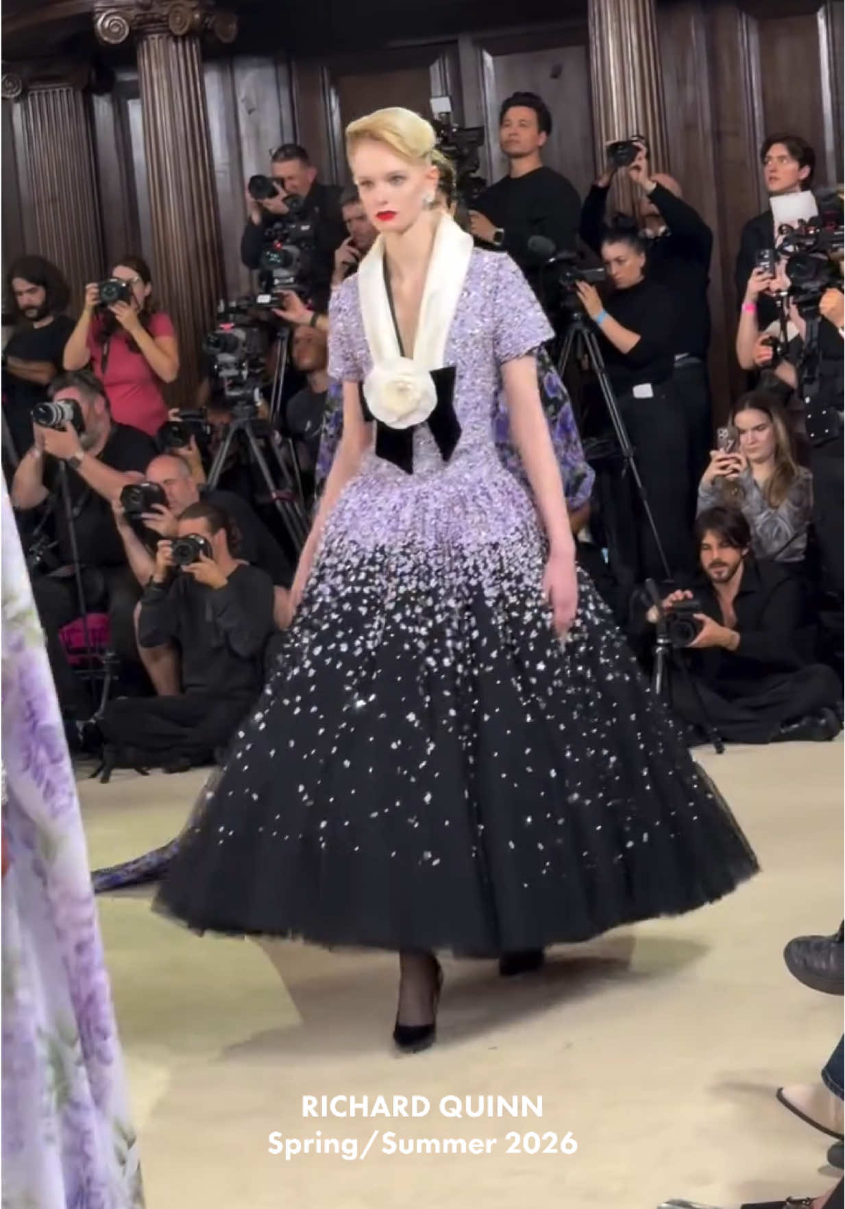 FASHION SAVE THE QUINN!  Desta vez, @Richard Quinn escolheu o palco de uma igreja barroca em Westminster para transformar seu desfile em um baile de noivas na @LONDON FASHION WEEK . Sob lustres de cristal e ao som de orquestra ao vivo, a coleção resgatou a grandiosidade do vestir aristocrático, tanto a rigidez da era vitoriana quanto o glamour americano do século XX. É um casamento perfeito de histórias. Foi a própria Elizabeth II, tataraneta da rainha Victoria, quem concedeu ao estilista, em 2018, o Queen Elizabeth II Award for British Design. Agora, ao enfatizar criações para o mundo das noivas, ele revisita justamente o universo que moldou a corte inglesa: Victoria, que eternizou a imagem da noiva em branco, mas também a soberana que, após a morte do príncipe Albert, fez do preto absoluto um uniforme de poder e saudade, influenciando os códigos do vestir no século XVIII e do luto aristocrático. Um mero tributo à realeza? Richard Quinn se coloca como intérprete de um ritual que, século após século, segue como padrões de status e solenidade.  Gostaram da coleção? Qual o seu veredito final?👀 📸: @tianweizhang  #moda #jornalismodemoda #fashion #moso #richardquinn  