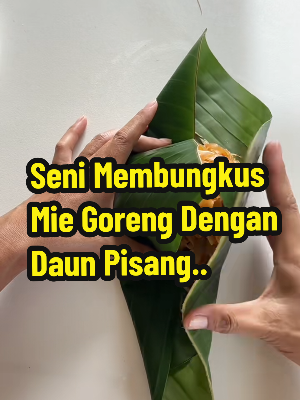 Dalam video ini, Anda akan melihat cara unik dan tradisional mengemas makanan menggunakan daun pisang. Tangan yang terampil menunjukkan proses melipat daun pisang menjadi kantong segitiga yang rapi, lalu mengisi dengan mie goreng, dilanjutkan dengan mengikatnya menggunakan tali dari serat alami. Setelah itu, sepasang sumpit disisipkan ke dalam paket sebagai aksesori praktis. Hasil akhirnya adalah sebuah kemasan ramah lingkungan, estetis, dan siap dibawa pulang, menggabungkan keindahan budaya lokal dengan praktikalitas modern. English - In this video, you'll witness a unique and traditional method of food packaging using banana leaves. Skilled hands demonstrate how to fold the leaves into a neat triangular pouch, fill it with stir-fried noodles, and secure it with natural fiber string. A pair of chopsticks is then inserted for convenience. The final result is an eco-friendly, visually appealing, and portable meal package, blending cultural heritage with modern practicality. #KemasanDaunPisang #MieGorengTradisional #RamahLingkungan #SeniMengemas #CaraUnikMakan 