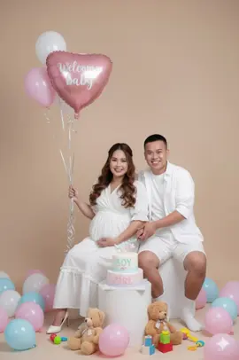Welcome baby 💕💕💕 —————— Prompts for Welcome Baby Photo Shoot Prompt: Hyper-realistic 8K studio photo shoot for a baby welcome celebration. • Subject: A smiling couple, male and female. • Female Attire: A white dress that covers her belly with delicate ruffles, white high heels, and long, wavy brown hair. Her makeup is soft and beautiful, with clean, glowing skin. • Male Attire: A white shirt over a white t-shirt, white shorts, and white socks. • Setting: Both are seated on a small white cylindrical pedestal. • Additional Elements: • The woman is holding a silver balloon string attached to a large pink heart-shaped foil balloon that says, 