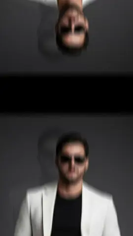 ركز بهاية الكشخة القوية  ‏Make this image to a stylish man standing confidently, wearing a white suit jacket and matching trousers, paired with a black t-shirt. He has a beard and is wearing sunglasses. His hands are in his pockets, and his legs are crossed at the ankles. He is wearing white sneakers. The background is a dark, gradient gray, with a faint, ghostly reflection or outline of the man behind him. The lighting is focused, highlighting the man, creating a chic and fashionable aesthetic.