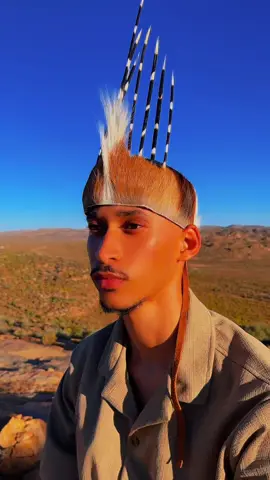 On this Heritage Day, I wear my story. The crown upon my head speaks of the Khoi, whose spirit flows in my blood, guiding me with dignity and pride. The earth-toned colors of my attire echo the roots of my Khoi and San ancestors, a reminder that neutrality can hold the richness of history. Yet, as a Coloured South African, my story is a book consisting of many chapters. The shorts I wear nod to the Boers — settlers who, too, became part of my lineage many years ago. Upon my feet rest brown leather shoes, the very style once worn by the Nama uncles whose footsteps shaped the lands I walk dayly.  And in my hand, I carry my great-grandfather’s herder’s stick — not just a symbol of labour, but of legacy, guidance, and resilience.  I am not just one chapter of history. I am the book — written by ancestors who refused to be forgotten.  #namakwalander🌻🌼 #tiktoksouthafrica 
