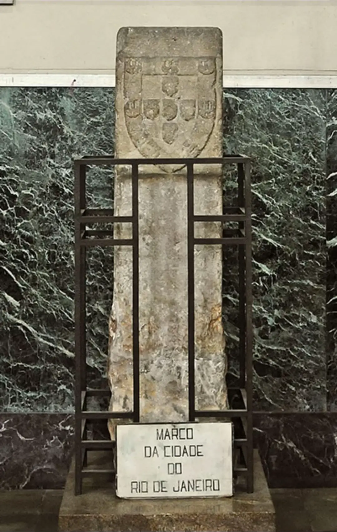 O Marco da Fundação da Cidade do Rio de Janeiro na Basílica Santuário de São Sebastião (Igreja dos Capuchinhos) Tijuca  🇵🇹🇧🇷 O Marco da Cidade de São Sebastião do Rio de Janeiro teve como localização original o Bairro da Urca, zona Sul da cidade, entre o Morro Cara de Cão e o Pão de Açúcar.  Sendo este o local escolhido por ser o local do início da colonização portuguesa no Rio de Janeiro, a partir do ano de 1565, com a vitória de Estácio de Sá sobre os franceses que tentavam fundar uma colônia aqui, a França Antártica.  Possui gravações em relevo em ambas as faces; em uma delas, as Quinas Portuguesas e na outra face, a cruz, cujos galeões e caravelas do tempo da fundação da cidade usavam como estandarte.  Mede aproximadamente 2 metros e meio de altura.  Encontramos nos simbolos do escudo da Coroa Portuguesa, sete castelos, representando as sete cidades que D. Afonso Henriques conquistou aos Mouros: Coimbra, Óbidos, Santarém, Lisboa, Palmela, Ourique e Évora. Na parte central destacam-se as chamadas cinco Quinas ou Escudos de cor azul simbolizando os cinco reis Mouros que Dom Afonso Henriques derrotou e dentro destes encontramos as cinco Chagas de Cristo pois desde a sua primeira bandeira que El Rei levava consigo a Cruz de Cristo na bandeira, simbolizando a aliança  do Reino Português com Deus. O monumento passou por diversas trocas de local. Este monumento e os restos mortais de Estácio de Sá, morto em 1567, foram transladados do Morro Cara de Cão para o Morro do Castelo, ainda no século XVI. Por volta de 1843, a Igreja de São Sebastião, que ficava no Morro do Castelo, foi repassada aos Capuchinhos italianos, que reformaram a igreja e assentaram o marco no seu lado externo. Após o desmonte do Morro do Castelo em 1922, este monumento foi colocado no centro da nova Praça da Esplanada do Castelo, local exato de onde ficava a igreja dos capuchinhos antes do desmonte. Posteriormente, o monumento foi levado para o seu novo local, onde foram instalados os Capuchinhos após o desmonte do Morro do Castelo, inicialmente na Rua Conde de Bonfim, na Tijuca. Depois, foi novamente transladado para a Igreja de São Sebastião, padroeiro da cidade, e também conhecida como 