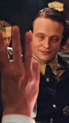 Did you know a simple hand gesture becomes a fatal giveaway in Tarantino’s Inglourious Basterds? In the tense tavern scene, British spy Archie Hicox orders three drinks by raising his index, middle, and ring fingers—an English habit. A German would signal “three” with the thumb, index, and middle. That tiny cultural slip alerts the Nazi officer to his true identity, igniting the bloody shootout that follows. Tarantino builds the moment with quiet precision: a raised hand, a pause, and the slow realization that language isn’t the only thing that betrays us. How many secrets do we reveal every day in gestures we barely notice? #KindredRealms #VisualCulture #InglouriousBasterds #QuentinTarantino #CinemaDetails     