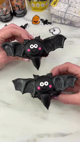 Bat-cakes 🦇🧁 Made for @Wilton Cakes 🖤 Turning cupcakes into spooky season bats complete with wings made from Black Candy Melts! 🖤Use melted Black Candy Melts to pipe a thick, curved line onto parchment paper and spread using  an offset spatula, then shape  wings using a small decorating brush and let set (once set, spray with Edible Silver Glitter spray and keep them in the fridge) 🖤Shape cupcakes into hearts shapes using piping tips or alumnium foil between the liner and the cupcake pan before baking  🖤Once cool, use black buttercream and piping tip 1A to add a round head and a body on each cupcake and leaf tip 352 for the ears  🖤Add two small Edible Candy Eyeball Sprinkles and two flat pink confetti sprinkles for the cheeks #cakedbyrach #spookycute #cupcake #halloweenbaking #cakedecorating 