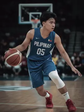 Gemini AI prompt: Create a hyperrealistic photo of me as a basketball player, captured in a dynamic moment on the court, mid-dribble. My body is leaning slightly forward and to the right, with my right leg bent and extended forward, and my left leg trailing, just lifting off the ground as if pushing off. My right arm is extended down, controlling the basketball with my hand on top of it, while my left arm is slightly bent at the elbow and held close to my body for balance. My head is turned slightly to the right, eyes focused intently forward, surveying the court. I am wearing a Blue Pilipinas basketball jersey with 'PILIPINAS' written across the chest and the number '05' below it, Blue shorts, white knee support, white short socks and red basketball shoes. The background is a slightly blurred but recognizable basketball arena with spectators in the stands and a basketball hoop visible behind me. 4K resolution.