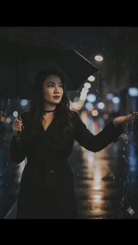 Gemini AI Edits  1. Open Gemini 2. Upload photo 3. Paste the prompt Reimagine this photo into a Subject: A serene and stylish woman with long, dark hair, holding a black umbrella over her shoulder with her left hand. She is looking away to her right, with her right hand extended to catch the falling raindrops. She's wearing an elegant black outfit consisting of a belted coat or blazer, and a black choker. Setting: The setting is a dark, rainy urban street at night. The background is softly blurred, creating a bokeh effect from the distant city lights and building windows. The streetlights and other sources of light are out of focus, appearing as glowing orbs of color. Lighting and Atmosphere: The lighting is dim and dramatic, with a gentle glow from the background lights. The focus is sharp on the subject and the rain, which is visible as bright, crisp streaks and splashes. The atmosphere is quiet, contemplative, and cinematic, with a moody and romantic feel. The colors are muted, dominated by black, gray, and the warm, blurred lights of the city. #fyp #aiprompt #gemini #aigenerated #ai