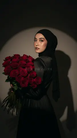 #prompt: Create a portrait of a beautiful young woman holding a large bouquet of red roses. My face uses the attached image, posing elegantly, turning her back over her shoulder. She wears black hijab and a luxurious black dress. The background is a soft spotlight, creating a dramatic circular shadow. High detail, cinematic lighting, smooth skin, delicate makeup, romantic atmosphere, fashion photography style.  #fyp #fypage #trending #geminiai 