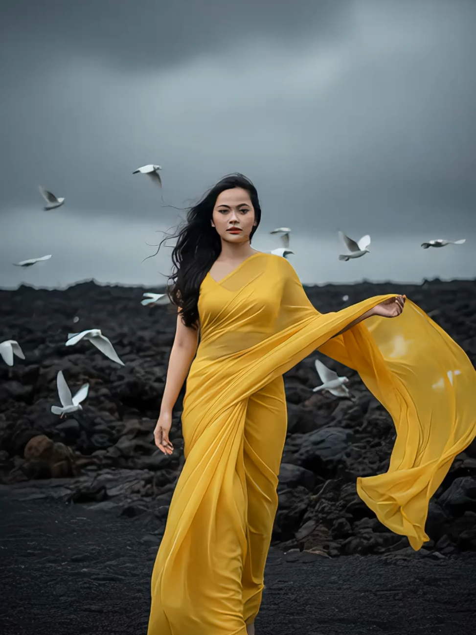 ya ampun berasa jadi kajol 😭 cantik banget hasil nya 😭😭 prompt: Buatlah aku dengan foto wajah ku tanpa mengubahnya sedikit pun menjadi Seorang wanita anggun mengenakan saree kuning cerah berbahan ringan yang berkibar indah tertiup angin. Pose tubuhnya elegan, berjalan anggun  ke depan menghadap kamera dengan tatapan penuh percaya diri. Dengan satu tangannya memegang kain saree nya ke atas, Kain saree yang panjang menciptakan efek dramatis seolah melayang di udara. Rambut panjang hitam bergelombang yang tertiup angin dengan banyak burung putih yang berterbangan di dekatnya.  Latar belakang: pemandangan alam gelap atau bebatuan hitam, yang memberi kontras kuat. #geminiai #caraeditai #saree #gerua #fyp 