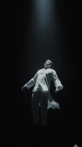 A surreal cinematic photo of a person floating weightlessly in mid-air under a single dramatic spotlight, surrounded by vast darkness. The figure appears to be gently suspended, body slightly arched backward with relaxed arms hanging downward, as if defying gravity. A flowing, elegant, male garment Loose white shirt and loose pants, drapes naturally and sways with a soft sense of motion, emphasizing the levitation. Lighting is high contrast with a cool bluish tone, spotlight cutting through subtle haze, creating a mystical and ethereal mood. Camera angle is low and tilted upward, reinforcing the illusion of elevation and height. The overall atmosphere feels dreamlike, otherworldly, and cinematic.