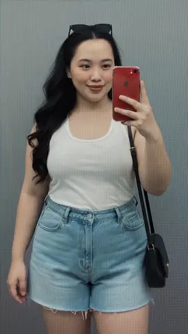 A portrait of a chubby woman (based on uploaded photo for reference) taking a mirror selfie, wearing black sunglasses on her head, a long straight hair , light beige racerback top , black high waisted shorts, and a black shoulder bag. The setting is minimalist with a beige wall and a white light switch. She is holding a black phone in her right hand and smiling slightly. Casual, modern, and elegant style. #prompt #ai #foryoupage #foryou #fyp 