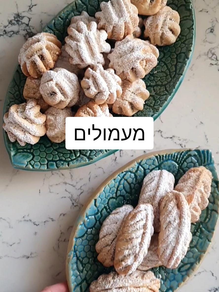 הינה המתכון לעוגיות מעמול תמרים בניחוח הדרי בשני עיצובים קלאסים הכנה פשוטה, שלב שלב. הן נמסות בפה וקלות להכנה בלי מקסר הכל בקערה אחת. עוגיות פרווה מושלמות! גם לשבירת צום יום כיפור: לבצק 400 גרם קמח 100 גרם סולת 2 כפיות אבקת אפייה 1/4 כוס סוכר 1/4כפית מלח 200 גרם מרגרינה בטמ'פ החדר 1/4 כוס שמן כפית תמצית וניל 1/3 כוס מים קרים למלית חבילת תמרים מגולענים בוואקום גרידת תפוז כפית מי זהר 1 כף דבש מיץ סחוט מתפוז אחד שלם (אפשר להוסיף גם אגוזים טחונים גס) קינמון (ששכחתי לצלם) ההכנה: שמים את כל מרכיבי הבצק בקערה ולשים רק עד שנוצר בצק רך. שמים את כל מרכיבי המלית בקערה נפרדת ולשים ביד לקבלת עיסה יציבה. בידים מעט משומנות יוצרים  כדורים קטנים מעיסת התמרים (משקל כל כדור בערך 12 גרם). לוקחים חיתיכת בצק קטנה (בערך  במשקל 20 גרם) משטחים ביד  ומניחים כדור תמרים. מגלגלים שהכדור יהיה עטוף כולו בבצק. חוזרים על הפעולה עם שאר הבצק.  בעזרת פינצטה שמיועדת להכנת מעמולים, צובטים כמו בסירטון ליצירת דוגמא יפה. מסדרים את המעמולים ל גבי תבנית מרופדת בנייר אפייה ואופים בחום בינוני למשך 25 דקות או עד הזהבה. מצננים, בוזקים אבקת סוכר ומגישים. גמר חתימה טובה❣️ #עוגיותמעמול #עוגיותפרווה 