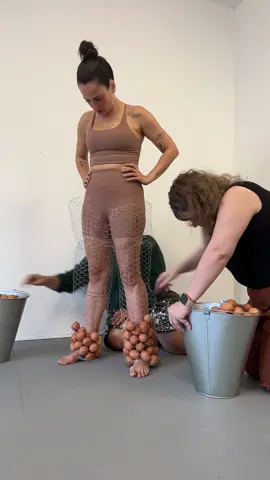 Fazer 40 anos me colocou frente a um monte de perguntas que não foram minhas. Existe uma pressa que não é minha, uma urgência do lado de fora do corpo. Decidi transformar esse incômodo em performance, dar forma ao peso dessas expectativas. Visto uma estrutura de tela de galinheiro moldada como um corpo. Fico dentro dela, parada, enquanto um assistente coloca ovos de galinha brancos, um por um, preenchendo essa 