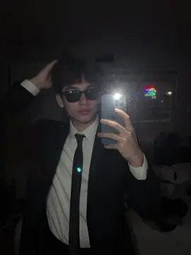 🔥 PROMPT:Person in the image [DO NOT CHANGE SUBJECT'S FACIAL FEATURES] A very ordinary iPhone mirror selfie with no clear subject or framing; a careless snapshot. The photo has a little motion blur and is slightly overexposed due to uneven light. The angle is awkward, the composition is non-existent, and the overall effect is aggressively mediocre – like an accidental photo taken while taking the phone out of your pocket to take a selfie .The subject takes a shaky iPhone mirror selfie at night, before he goes out. He wears a classic black suit jacket over a crisp white dress shirt, finished with a slim black tie that’s slightly loosened at the collar and a sunglasses. The white shirt cuff peeks from the sleeve He is styling his hair. in a dimly lit room with no lights on except for the harsh phone flashlight, which creates stark highlights and blown-out reflections. The phone is very close to the mirror. The photo has a vertical aspect ratio of 9:16. Neon lights are faintly visible from the outside. #fyppppppppppppppppppp 