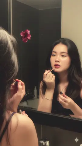 Gemini Ai Prompt: Create a photo of me in a warm, candid shot of a young woman with long, wavy dark brown hair, seen from the chest up, applying lip gloss in a bathroom mirror. Her reflection is visible in the foreground on the left, showing the back of her head and shoulder. The woman in the reflection is looking intently at her lips while applying the gloss with a wand. She has a natural makeup look with a focus on defined eyes and soft, full lips. Her skin is clear with a healthy glow. She is wearing a simple dark top, possibly a tank top or camisole, revealing her bare shoulders. On her left arm, she wears a delicate bracelet and a ring on her ring finger. ‎The bathroom setting is dimly lit with warm ambient light, giving the image a soft, slightly grainy, and intimate feel. The mirror has a dark frame, and behind her in the background, out of focus, are dark tiles and some toiletries on a shelf or counter, including a small bottle she's holding in her left hand, possibly more makeup or a drink. The overall aesthetic is natural, relaxed, and slightly retro due to the film-like quality. Keep the facial details correctly. Please do not alter my facial features and leave the head positioning as is in the reflection and the primary view. #fypシ #geminiai  #foryouuuuuuuuuuuuuuuuuuuuuuuuuu #edit #CapCut 