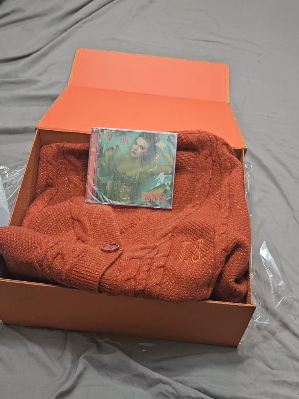 Unboxing my The Life of a Showgirl Cardigan box set! I love it! the cardigan is super sparkly (im wearing now). the box is smooth glitter that does come off, the logo is embossed&metallic and the magnents on the flap are pretty strong. I WILL be wearing this to the movie theater 😌🧡🧡🧡 #thelifeofashowgirl #taylorswift #cardigan #taylorswiftcardigan #orangecardigan 