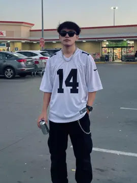 Ini promptnya:Foto street style bergaya urban di area super market. Seorang pria dengan wajah 100% identik dari foto referensi saya berdiri santai sambil memegang minuman kaleng. Dia mengenakan jersey football oversized warna putih dengan nomor besar 