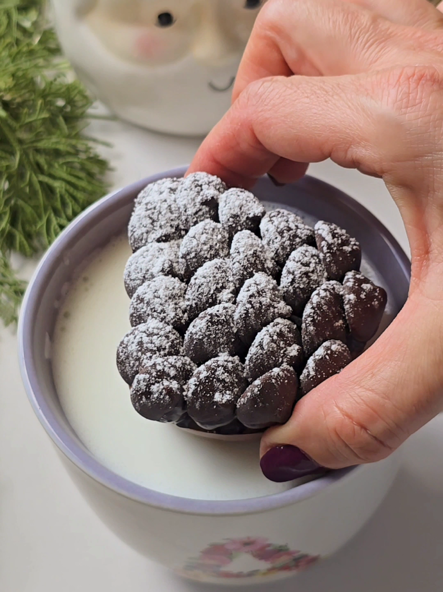 Pinecone Hot Cocoa Bomb ☕️🍫🎄 An old technique with a new twist 🤎 Directions: Cut out the standard half spheres silicone mold's cavities. Line with melted milk or dark chocolate. Place into the cupcake tin. Fold the kitchen foil into thin rectangles and place on the upper sides of each silicone mold to form cone shape. Freeze for 15-20 minutes until solid. Remove from freezer and remove foils. Add 1 tbsp hot cocoa mix and mini marshmallows. Top and smooth with melted chocolate. Place into freezer to set for 20-30 minutes. Remove from freezer and demold. Adhere dark chocolate heaves with bit of melted chocolate. Sprinkle powdered sugar. Enjoy in cup of hot milk!🎅☕️ #hotcocoabomb #hotcocoabombs #holidayseason #christmasideas #chocolate 
