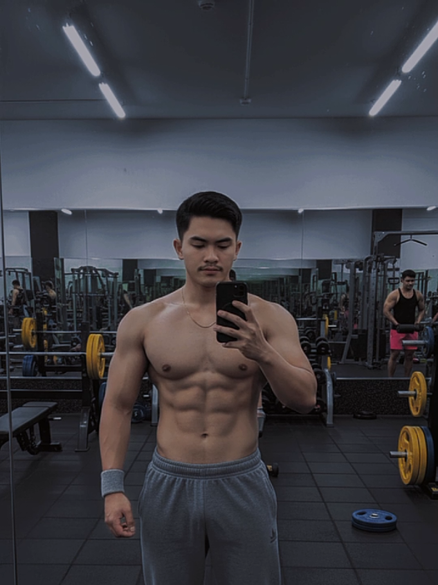 #CapCut Promt Gemini: Buatlah foto dari gambar yang saya unggah  Subjek utama: Pria berambut pendek tebal Tidak mengenakan atasan, memperlihatkan otot dada, perut, dan lengan yang sangat terdefinisi — tampak berotot dan memiliki body fat rendah. Kalung  Mengenakan celana panjang longgar model sport warna abu abu Menggunakan gelang pergelangan tangan abu-abu muda di tangan kiri. Memegang ponsel dengan casing berwarna gelap, tampak berfoto di depan cermin besar. Latar belakang: Ruangan gym dengan lantai karet hitam. Terlihat beberapa alat fitness, seperti barbell, bench press, dumbbell, dan pelat beban warna kuning serta biru. Ada cermin besar di dinding belakang yang memantulkan seluruh ruangan. Beberapa orang lain sedang berolahraga di belakang, salah satunya pria bertubuh kekar memakai tank top hitam dan celana pendek merah muda. Pencahayaan gym cukup terang, dengan pantulan cahaya di lantai dan cermin. #gemini #aitrend  #gym #fyppp 