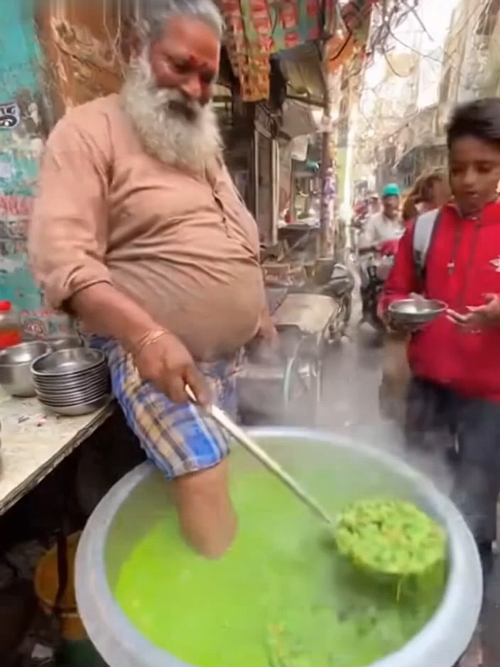 🍲 The Secret Ingredient of the Street Food Master 😳 In the heart of the busy streets, this legendary cook prepares his famous green curry. But here’s the twist : he stirs it with his own leg, claiming it’s his unique touch for richer flavor. Locals swear it’s the best soup in town, and people line up every day to taste it. No recipe book, no fancy kitchen just tradition, confidence, and a pinch of madness. They say if you can handle this, you can handle anything. #StreetFood #FinalBoss #India
