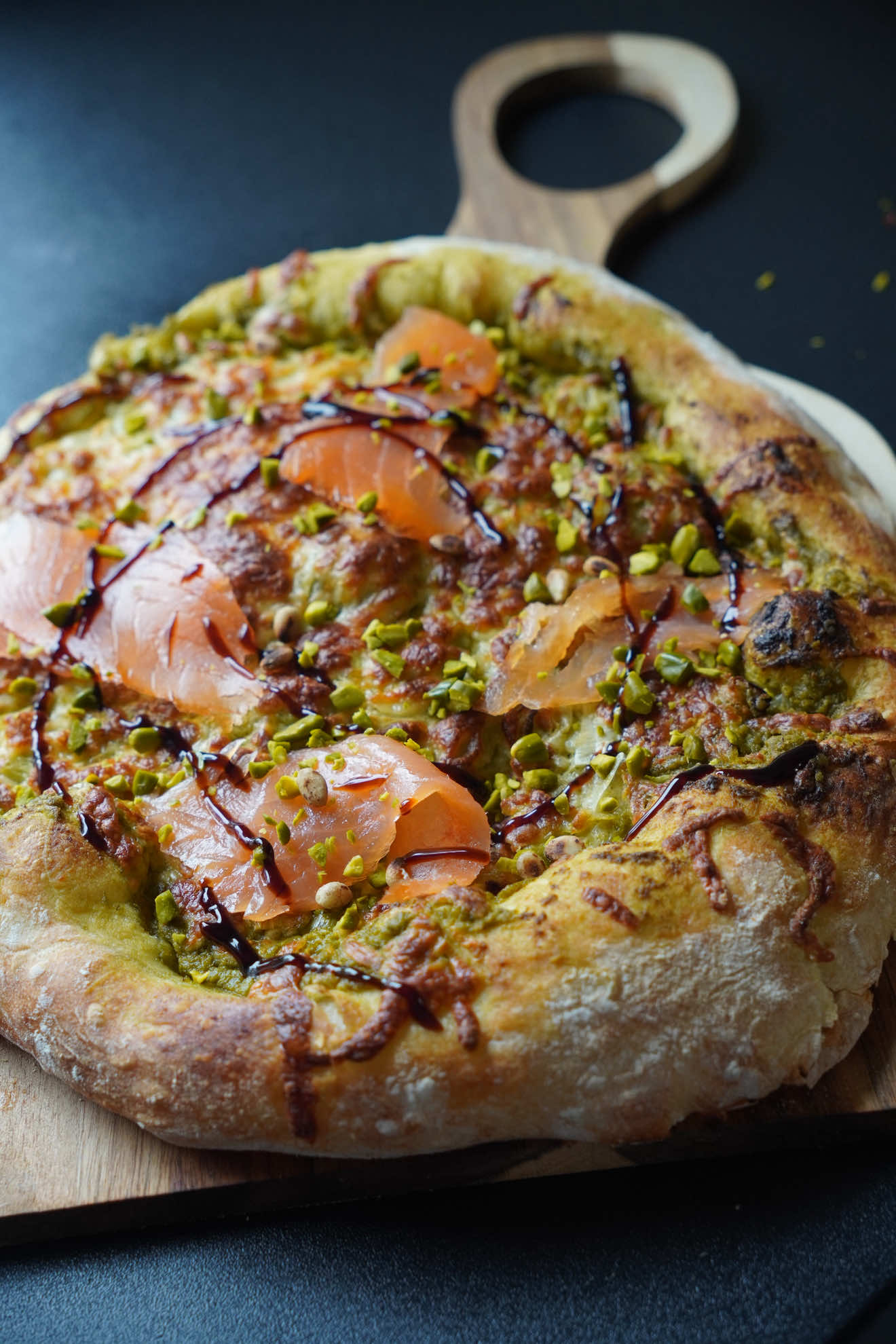 🍕 Pizza poireaux, pesto pistache & saumon Ingrédients 	•	1 boule de pâte fraîche de boulanger 	•	2 blancs de poireaux 	•	1 échalote 	•	1 noix de beurre 	•	1 c. à soupe de pesto de pistache 	•	3 c. à soupe de crème fraîche 	•	Mozzarella 	•	2 à 3 tranches de saumon fumé 	•	Quelques pistaches concassées 	•	1 filet de sauce balsamique 	•	Un peu de farine pour le plan de travail Préparation Fais revenir les poireaux émincés avec l’échalote dans un peu de beurre jusqu’à ce qu’ils soient bien fondants. Ajoute le pesto de pistache et la crème fraîche, puis mélange jusqu’à obtenir une farce crémeuse. Étale la pâte sur un plan fariné, nappe d’un peu de pesto, ajoute la farce et la mozzarella. Enfourne 8 minutes à 250 °C, mode pizza du four Smeg. La cuisson est rapide et homogène, la base bien croustillante et le fromage fondant. À la sortie du four, ajoute le saumon, les pistaches concassées et un filet de sauce balsamique. Un vrai goût de pizzeria à la maison !