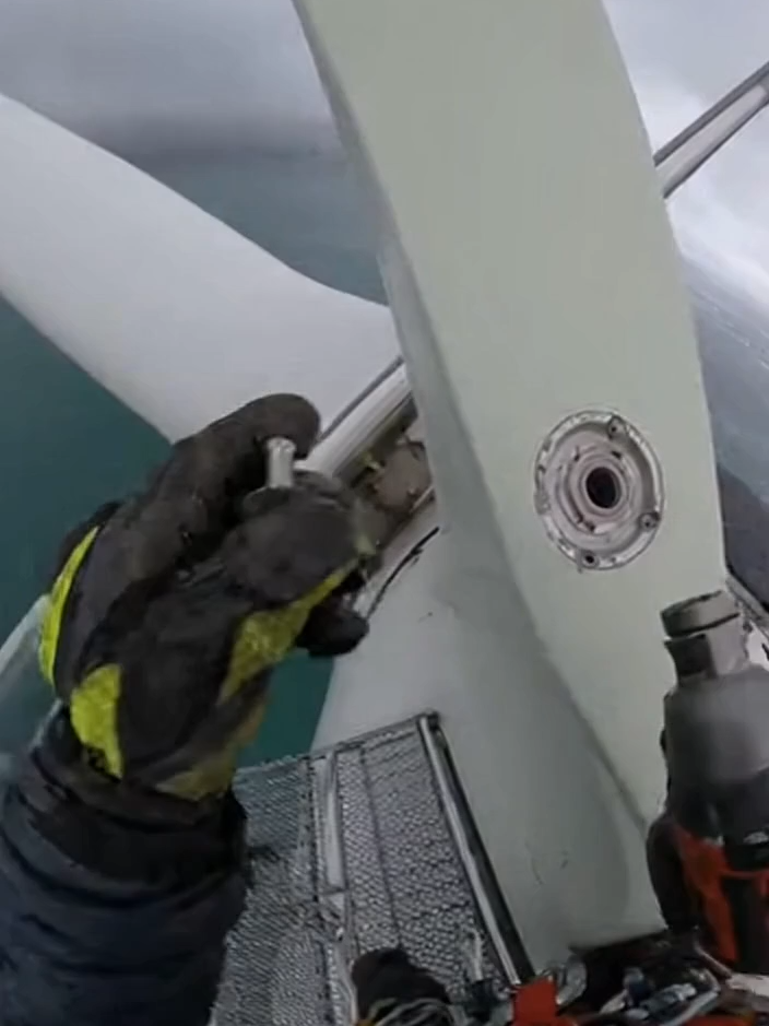 POV: You're an industrial climber - securing the final bolt on a wind turbine service platform