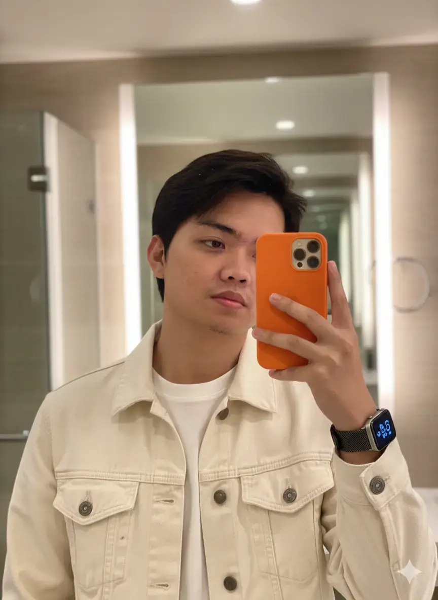 Prompt :  A close-up, high-detail portrait of an individual from the uploaded photo, taking a mirror selfie with an orange iPhone 17 Pro Max. The subject is wearing a cream/off-white denim jacket over a white t-shirt. An Apple digital watch is on their hand. The lighting is soft and warm. Ensure 100% of the face and body are from the uploaded photo. #aitrend #fyp #promptchallenge 