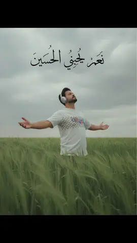 نعم يحبني الحسين /A cinematic, moody slightly telescopic shot of the person exactly as in the reference image, standing in a lush green field of tall grass, beneath a cloudy, overcast sky. Their face, body, and outfit remain unchanged from the reference image. The posture is expressive and dramatic, leaning slightly backward with one arm outstretched and palm open, as if embracing the wind or the moment. Their head is tilted back, eyes closed, and they are wearing large, over-ear silver headphones, evoking calm and emotional release. The perspective is slightly low-angle, with blurred grass in the foreground adding dreamy depth of field. The overall color grading is in muted green and gray tones, with soft, diffused natural lighting to create a serene, reflective, and slightly melancholic mood. The image should feel cinematic, atmospheric, and intimate, capturing a quiet moment of solitude and freedom.#تصميم_فيديوهات🎶🎤🎬 #CapCut #كسبلور_explor #كسبلور #تابعني_لو_حبيت 