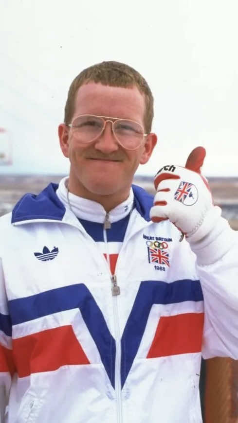 👇 Learn more 📚 Born in Cheltenham, England, in 1963, he became one of the most beloved figures in Olympic history, not for winning, but for daring to compete. Originally a plasterer by trade, he dreamed of representing Great Britain at the Olympics. When he failed to qualify for the national alpine skiing team, he realized that Britain had no active ski jumpers. So, he decided to become one. With no funding, no coach, and limited experience, he taught himself how to ski jump. He trained in Lake Placid, New York, and Finland, borrowing second-hand equipment, sleeping in his car or on friends’ floors, and surviving on cheap meals. His thick glasses fogged up mid-jump, but nothing stopped him. To qualify for the 1988 Calgary Winter Olympics, he needed to meet the Olympic minimum distance in an approved competition. He paid his own entry fees and scraped through with one successful legal jump, just enough to make history as Britain’s first Olympic ski jumper. At Calgary, he finished last in both the 70-meter and 90-meter events. But his energy, determination, and humor captured the hearts of millions. The crowd chanted his name. The media called him Eddie the Eagle.  After his unlikely success, the International Olympic Committee introduced stricter qualification rules, nicknamed the “Eddie the Eagle Rule” to prevent unqualified athletes from entering future Games. His story was later turned into the 2016 film Eddie the Eagle, starring Taron Egerton and Hugh Jackman, celebrating the spirit that made him unforgettable. #EddieTheEagle #OlympicHistory #WinterOlympics #SportsLegends #UnderdogStory       