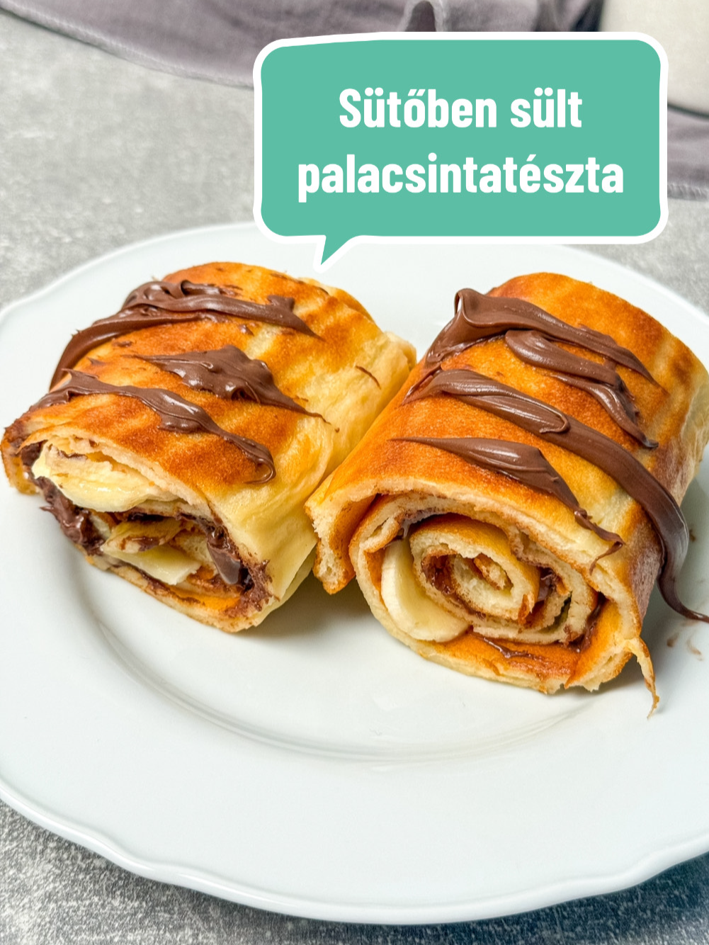 Palacsintatészta: sütőben sül aranybarnára Hozzávalók: Tészta: 2 db tojás 400 ml tej 0,5 dl olaj 170 g liszt 1 csipet só Töltelék: 5 ek. nutella 2 db banán Elkészítés: A tészta elkészítése hasonló a hagyományos palacsinta tésztához, egy csomómentes folyékony tésztát kell, hogy kapjunk. Törjük egy keverőtálba az egész tojásokat, öntsük fel a tejjel, olajjal, majd adjuk hozzá a lisztet egy csipet sóval és keverjük kézi habverővel csomómentesre. Egy nagyobb tepsit béleljünk ki sütőpapírral, oszlassuk el rajta a tésztát, ezután süssük aranybarnára légkeverésen 180 fokon 18-20 perc alatt. Ha elkészült kenjük meg nutellával és szórjuk meg vékony karikákra vágott banánnal. Egy tésztavágó segítségével, szeleteljünk hosszú csíkokat a tésztából, tekerjük fel szorogan, végül helyezzük egy tányérra és csurgassunk rá még egy kevés nutellát. Előkészítési idő: 5 perc Elkészítési idő: 25 perc Tepsi méret: 35×29 cm #fyp #őszirecept #nekedbelegyen #mutimiteszel #magyartiktok #sobors #sütőbensültpalacsinta #palacsinta #ovenbakedcrepe #desszert