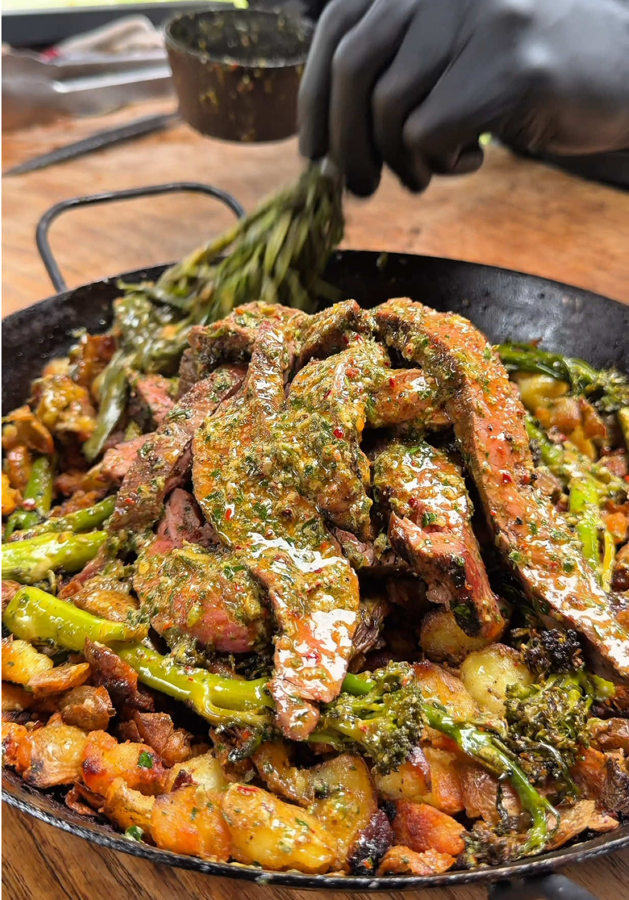 SERIES: ONE-PAN DICHES 3/5!!  Steak, Potatoes, Grilled Vegetables With Caper Lemon Butter Sauce!!  Flank steak, broccolini and smashed potatoes all in one pan, straight from the kamado. The potatoes were first cooked, then smashed with a glass and fried in duck fat for that perfect crunch. On top, a butter full of character: caper lemon chili butter fresh, spicy, and rich. Melted over the steak, veggies, and potatoes, bringing everything together in one creamy explosion of flavor. One pan. Full of fire, fat, and finesse. Van ’t Spit bij Smidt – Private Barbecue #steak #comfortfood #potatoes #veggies #foodtutorials 