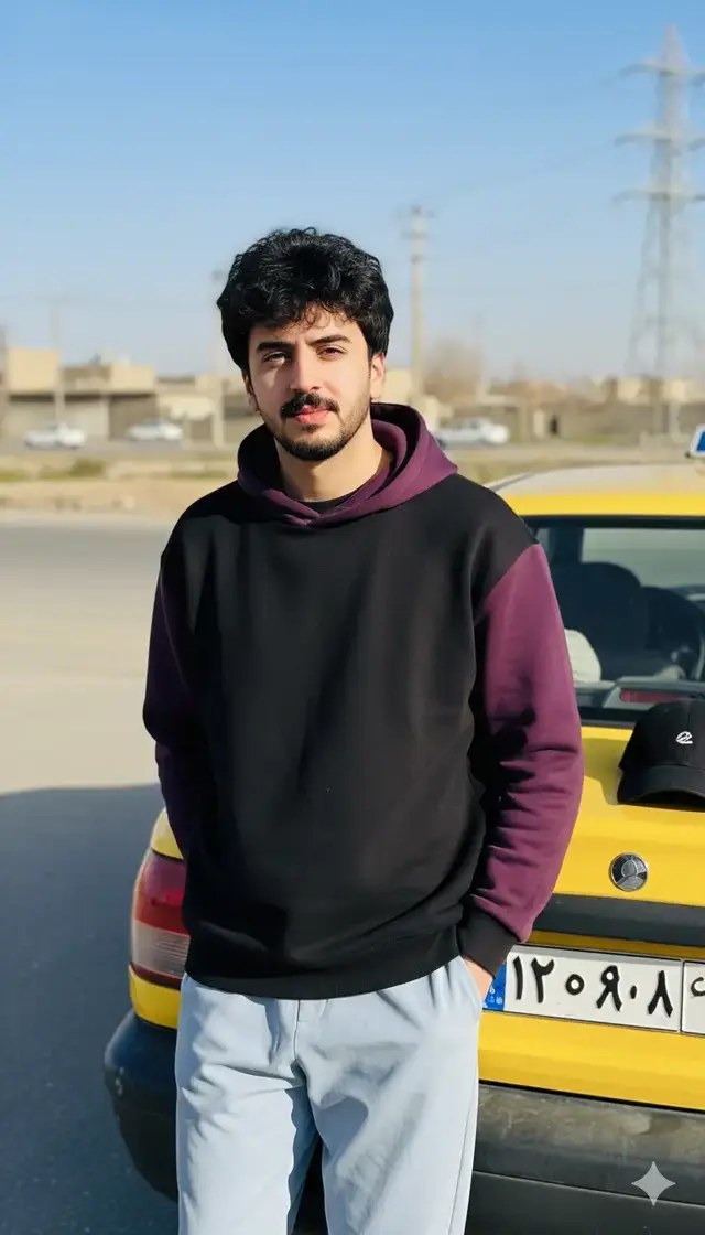 إنشاء صورة واقعية واستخدم وجه الصورة المُحمّلة بدقة وحافظ على ملامح وتفاصيل الوجه دون تغيير بدقة مثل الصورة المرفقة ​الشخص: يظهر شاب في  العشرينات، يرتدي سترة سوداء  عريضة فضفاضة  وبغطاء للرأس (هودي) باللون الأرجواني الداكن وبأكمام طويلة ملونة من الإمام بالأسود ومن الخلف بالارجواني، وبنطال رياضي عريض من القماش باللون الأزرق الفاتح/الرمادي . يقف  ويواجه الكاميرا مباشرة، مع ميل طفيف في الجسد يوحي بالاسترخاء والثقة. ​الخلفية الأمامية (العنصر المساعد): سيارة صفراء اللون (تبدو كأنها سيارة أجرة أو سيارة خاصة من النوع saipa)، حيث يستند الشاب خلفها مباشرة. يظهر غطاء رأس (كاب) أسود موضوعاً على صندوق السيارة. ​2. التكوين والإضاءة: ​التكوين: الصورة ذات تركيز قوي على الشخص، حيث يشغل جزءاً كبيراً من الإطار العلوي. تم وضع السيارة خلفه كخلفية مساعدة ولكنها واضحة ومكملة للمشهد. الكادر عمودي (بورتريه). ​الإضاءة: الإضاءة طبيعية قوية، على الأرجح في وضح النهار في وقت يكون فيه الشمس مشرقة ولكنها ليست في منتصف السماء (ربما الصباح المتأخر أو فترة ما بعد الظهر المبكرة)، مما يوفر إضاءة جيدة لوجه الشخص. هناك ظل خفيف أسفل الذقن، مما يشير إلى أن مصدر الضوء يأتي من الأعلى أو الأمام قليلاً. ​العمق: هناك عمق ميدان ضحل نسبياً (bokeh خفيف) يفصل الشخص والسيارة عنهما الخلفية البعيدة. ​3. الخلفية والبيئة: ​الموقع: تبدو البيئة وكأنها منطقة مفتوحة أو شارع جانبي في منطقة حضرية أو شبه حضرية. ​التفاصيل المعمارية/الطبيعية: الأرض ترابية أو رملية مع وجود أسفلت أو طريق في الخلف. تظهر بعض المباني البعيدة ذات الطابع البسيط وأعمدة كهرباء/نقل طاقة عالية في الأفق. السماء زرقاء وصافية مع القليل من السحب. ​دلالة البيئة: البيئة توحي بأن اللقطة ربما التقطت في منطقة سكنية أو صناعية بسيطة أو على طرف مدينة، وقد تكون في الشرق الأوسط (استناداً إلى نوع السيار(saipa) ولوحة الأرقام غير الواضحة تماماً ولكنها تبدو عربية). ​4. التعبير والمزاج العام (التحليل النفسي/الاجتماعي): ​التعبير: ،يدل على شعور جيد باللحظة والراحة أمام الكاميرا. ​المزاج: الصورة تعكس مزاجاً غير رسمي، شبابي، ومفعم بالحيوية والبساطة. هي لقطة 