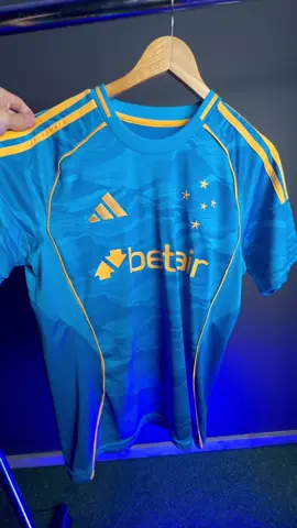 Um visual que honra a história celeste e se projeta para o futuro. O nosso Azul, agora com a força do contraste dourado. Da Toca da Raposa para o mundo! 🦊 Prontos para vê-la em campo? #CruzeiroEC #TimeDoPovo #MantoSagrado #LaBestiaNegra #YNWA 