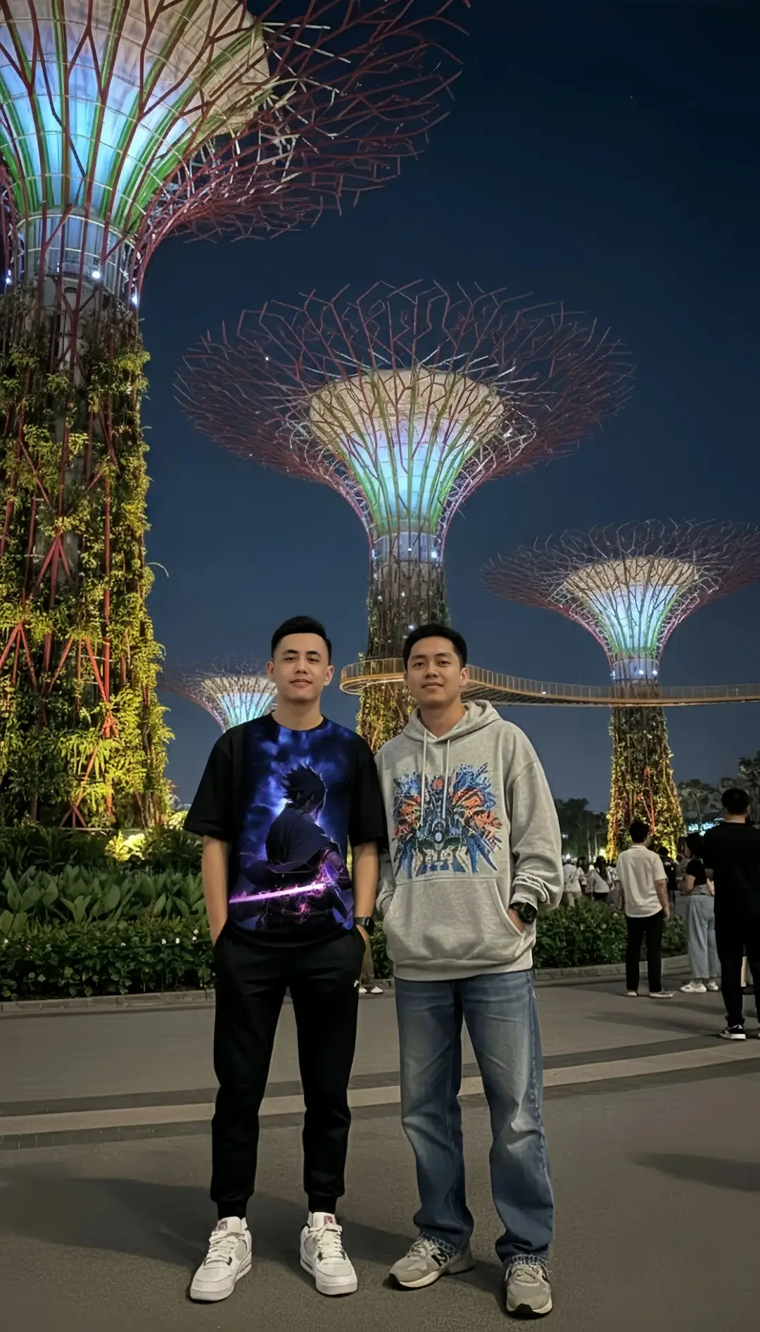 @ai.photolab.apk  PROMPT: Buat foto seorang pria muda bergaya berdiri percaya diri di malam hari di depan Supertree Grove yang bercahaya di Gardens by the Bay, Singapura. Pohon-pohon vertikal futuristik ini memancarkan cahaya berwarna putih, hijau, dan ungu yang menyoroti struktur logamnya di bawah langit malam yang jernih. Pria tersebut mengenakan kaos hitam oversized, celana hitam slim fit, dan sepatu sneakers putih, dengan tas selempang kecil hitam dan jam tangan pintar di pergelangan tangannya. Suasana foto terasa modern dan urban, dengan latar belakang orang-orang yang berjalan santai, taman yang rindang, serta pencahayaan dramatis yang menonjolkan keindahan arsitektur Supertree. Pencahayaan malam yang lembut membuat potret terlihat sinematik dan berkesan profesional, aspek 3:4. #naruto #fyp #faceswap #gemini #Ai 