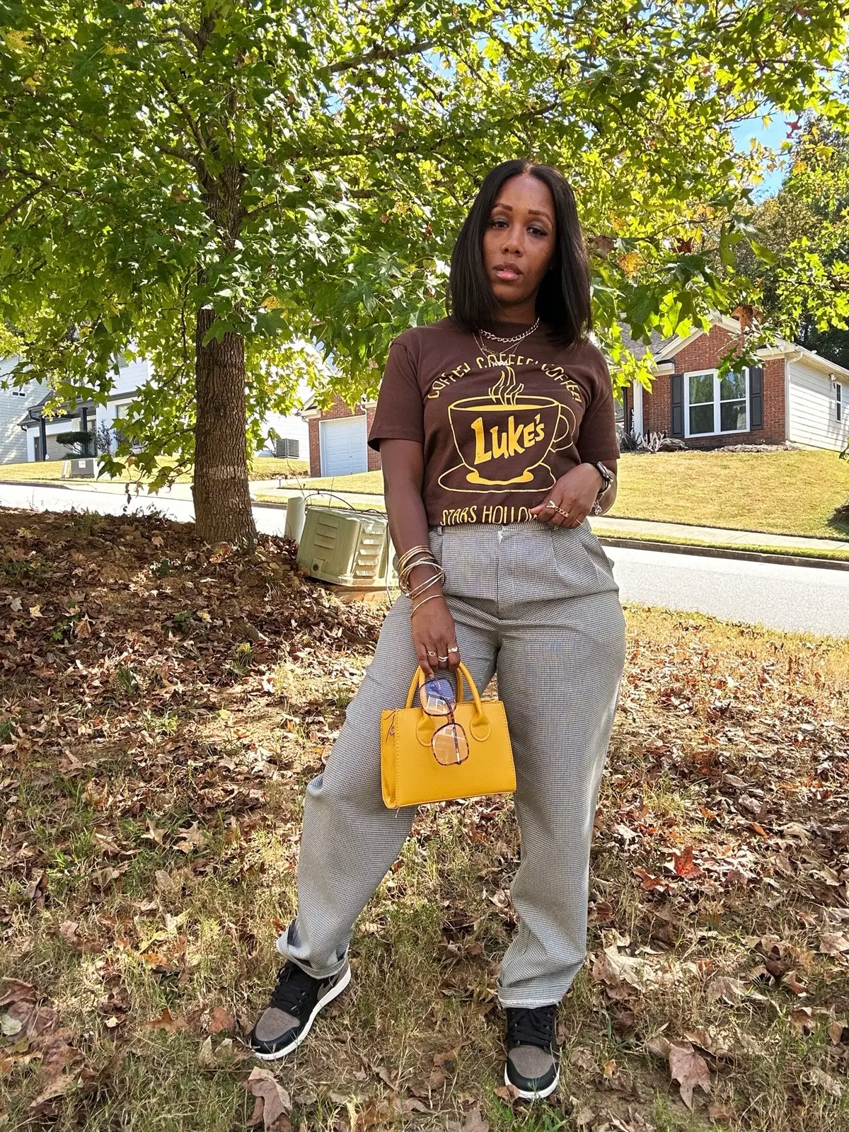 It’s starting to feel like Fall. Here’s an fall outfit idea that you recreate. I’m wearing a brown and gold graphic tee with black and white pleated pants. I styled this outfit with gold accessories, yellow purse, and Jordan 1 palomino sneakers