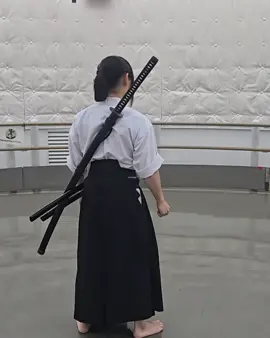 まーこ先生による大太刀の背負太刀（せおいだち）からの抜刀。 天心流では本来、左肩に柄が来るように背負い、背太刀（せだち）とも呼びます。 Maako Sensei drawing an odachi from the shoulder carry (seoi-dachi 背負太刀). In Tenshinryu, the sword is traditionally carried on the back so that the tsuka rests at the left shoulder; this method is also called Sedachi 背太刀.